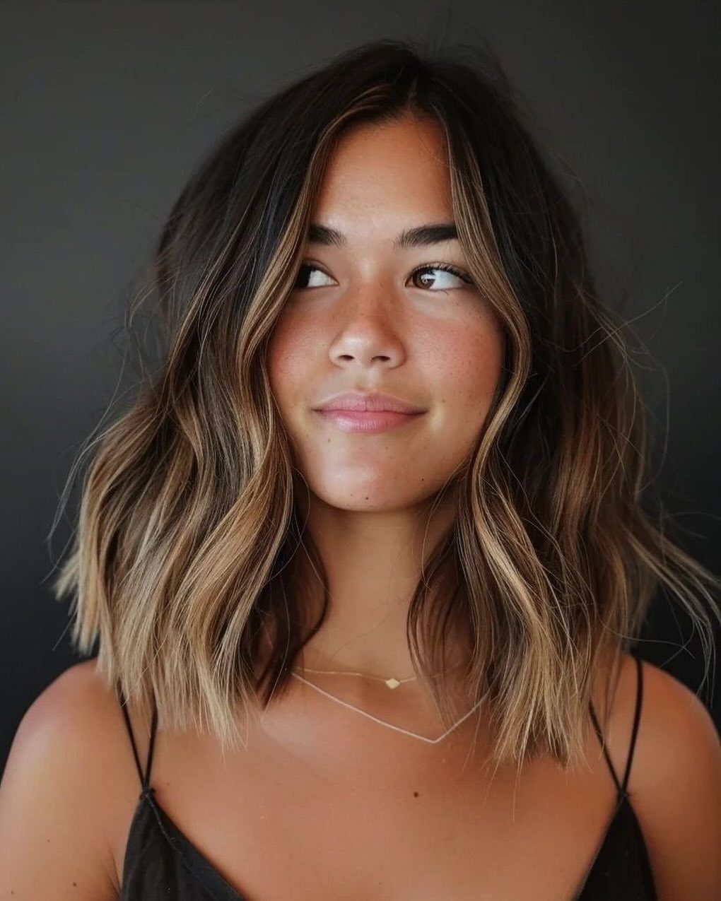 Woman wearing a wavy dark-to-blonde ombre lob with a center part