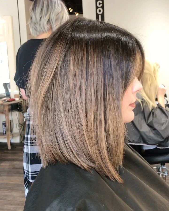 Woman with a sleek highlighted lob featuring tapered ends in a hair salon
