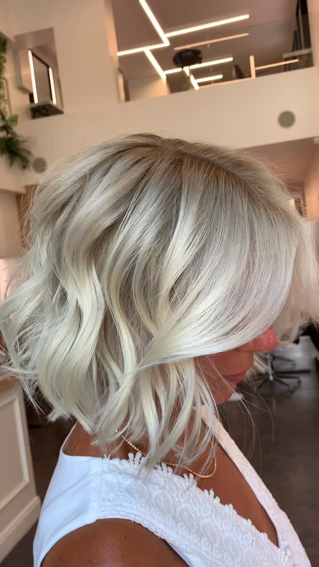 Tousled platinum layered bob with darker roots and side-swept front layers