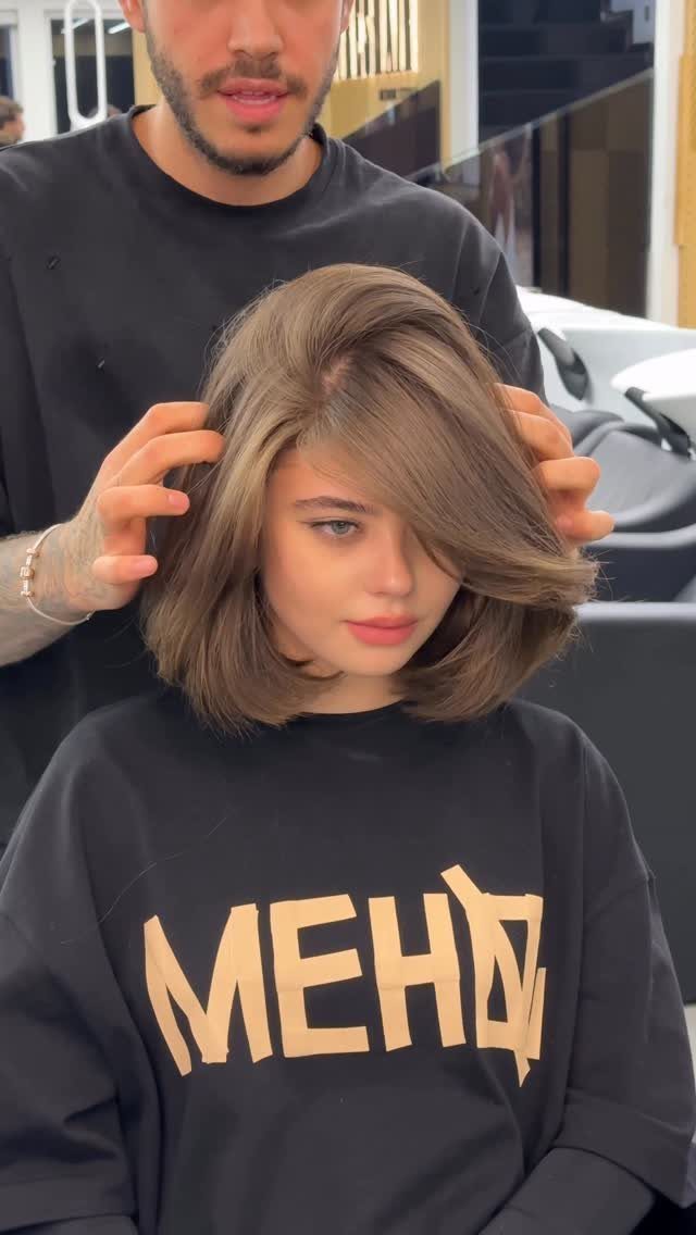 Woman displays a layered brown long bob with a voluminous side part in a salon