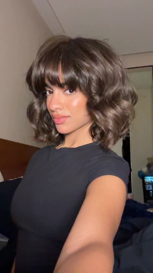 Woman showing a wavy dark bob with full fringe and face-framing curls