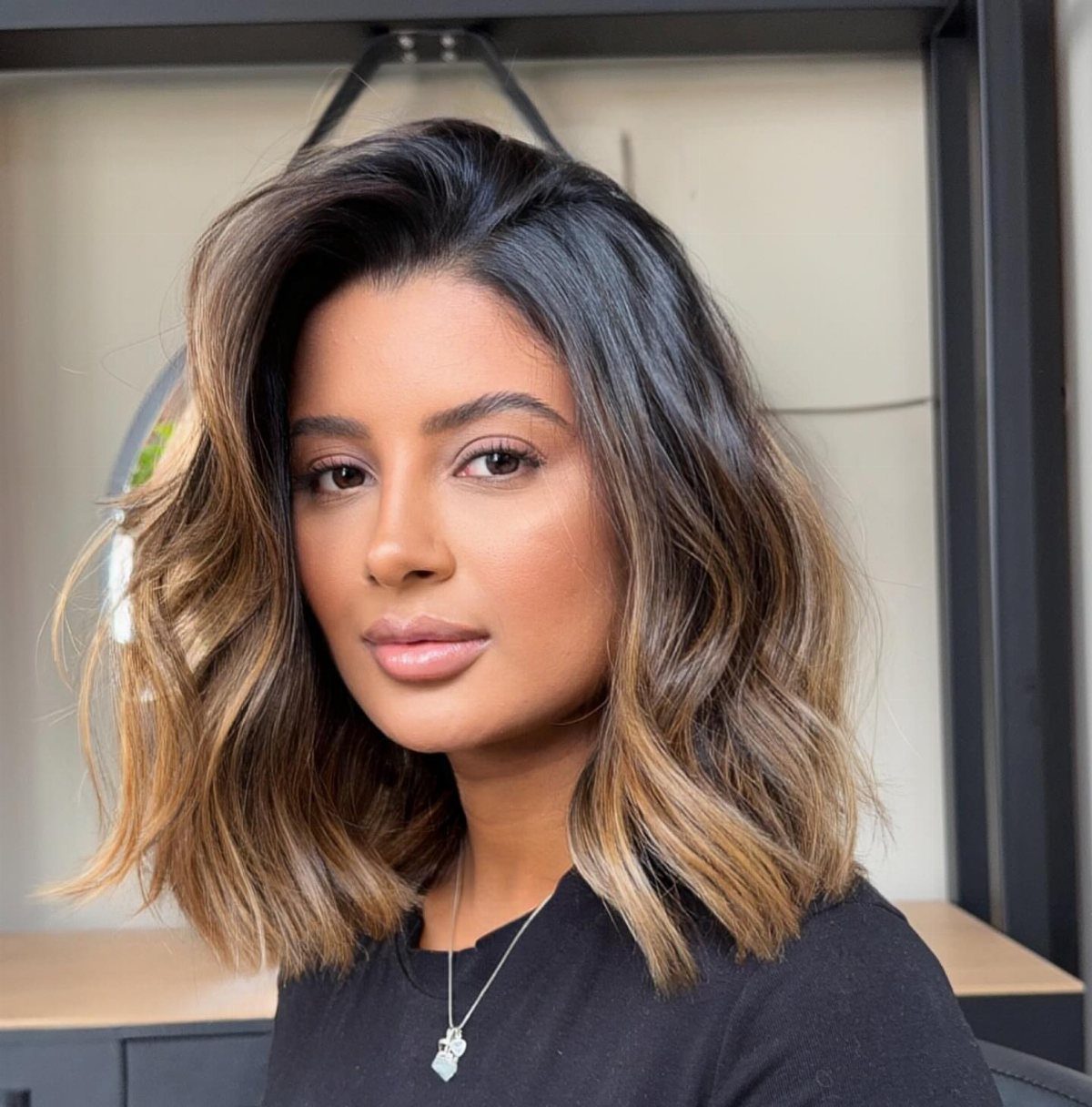 Woman with shoulder-length layered brown bob, lighter highlights, and loose waves