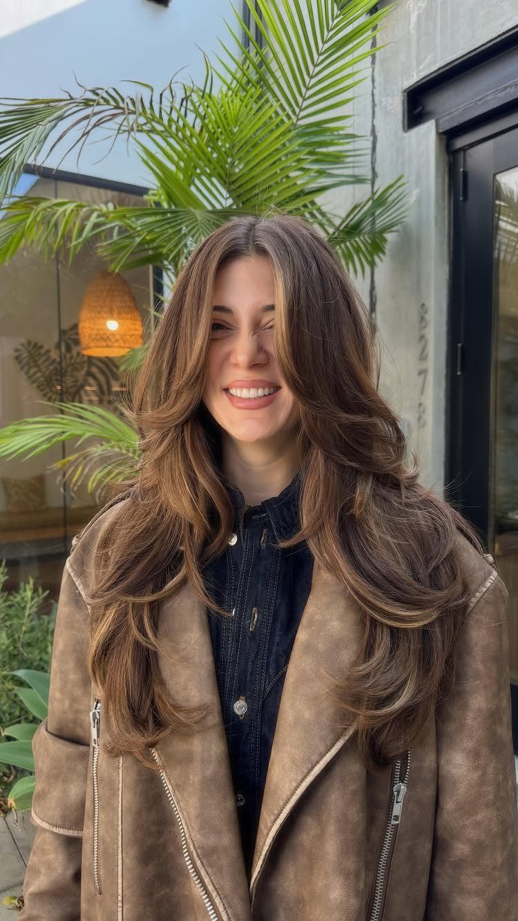 Woman with long brown curtain bangs and layered waves framing her face