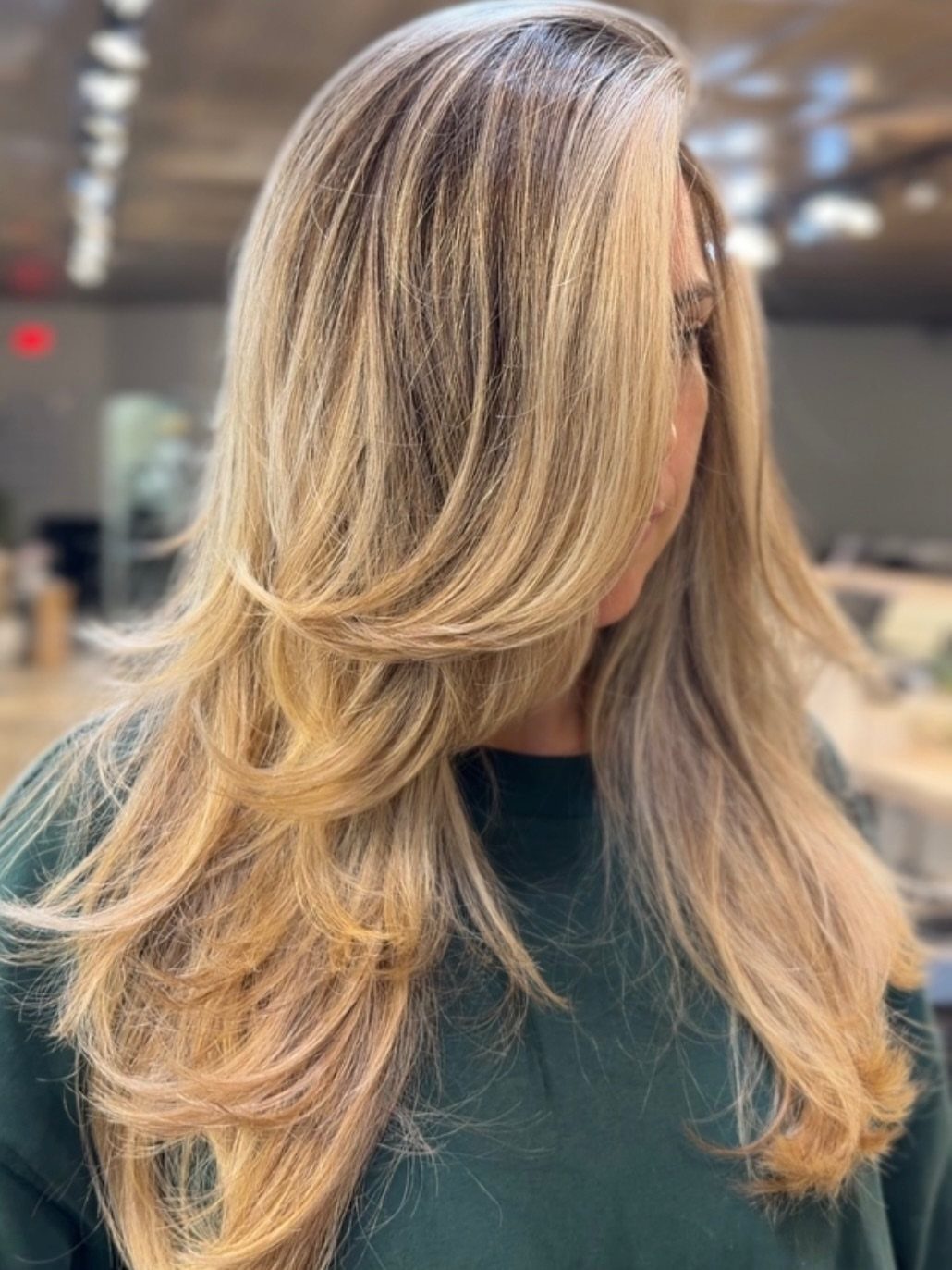 Long blonde hair styled in a voluminous, curved blowout with soft layers
