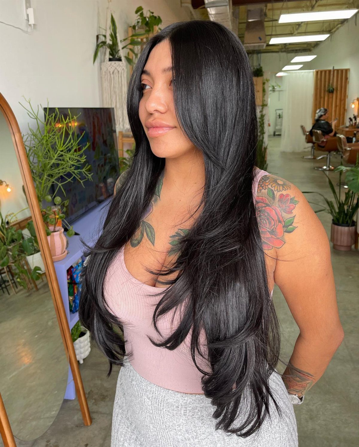 Woman with long glossy black hair styled in curved, feathered layers