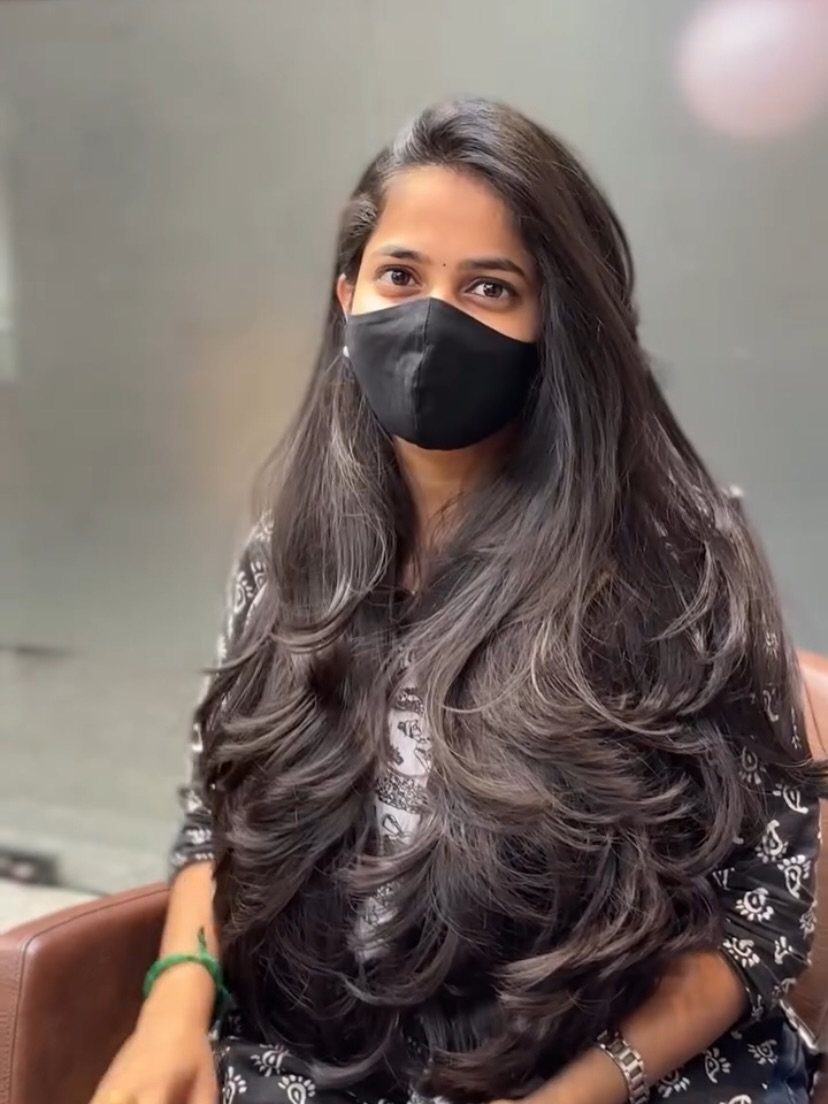 Woman with very long dark layered hair curled outward at the ends