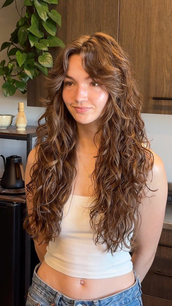 Woman with long, layered brown curls cascading over her shoulders