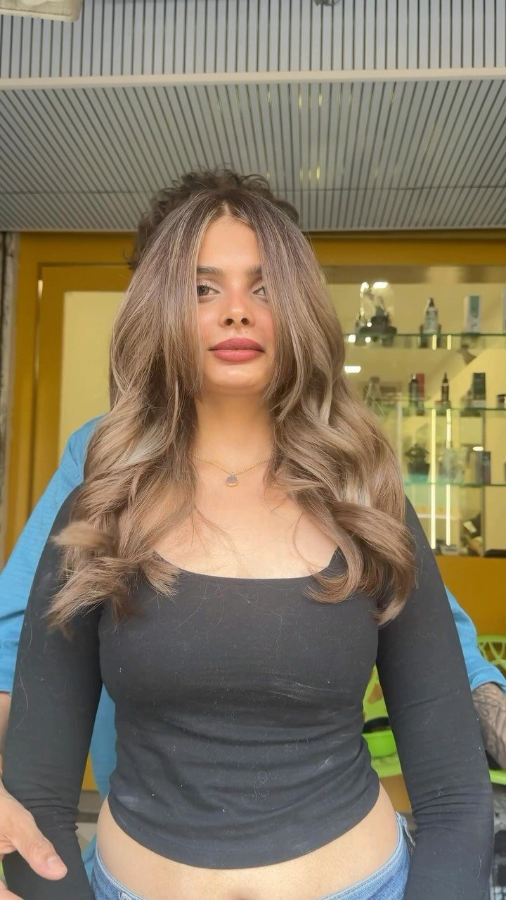 Woman with long sandy beige balayage layers styled in loose waves