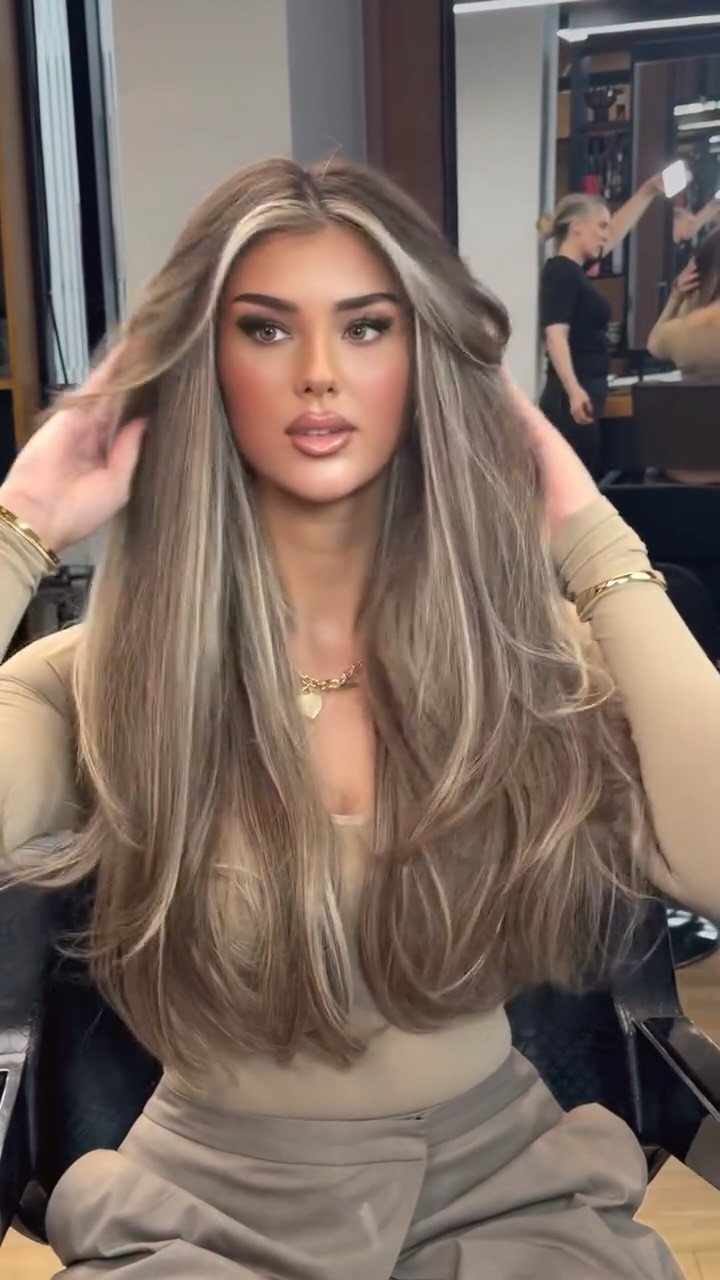 Woman showing long straight blonde layers in a salon chair