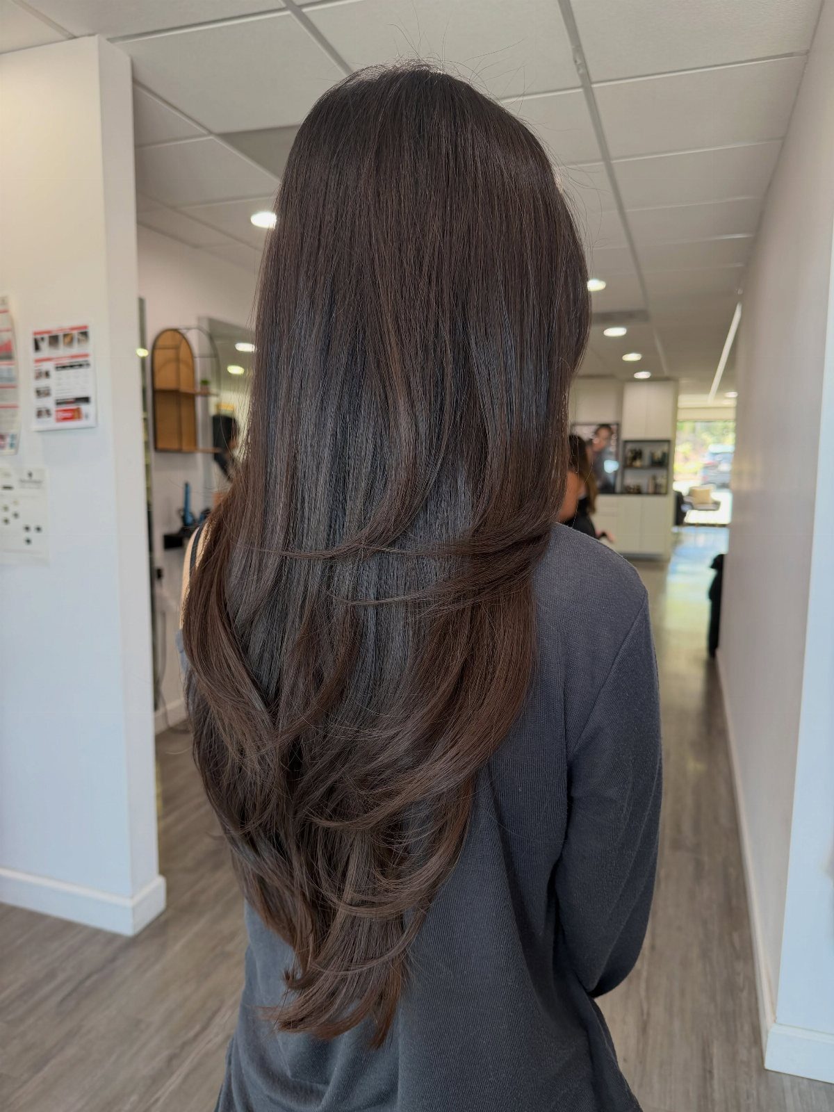 Long dark brown hair falls in smooth layers with gently curved ends