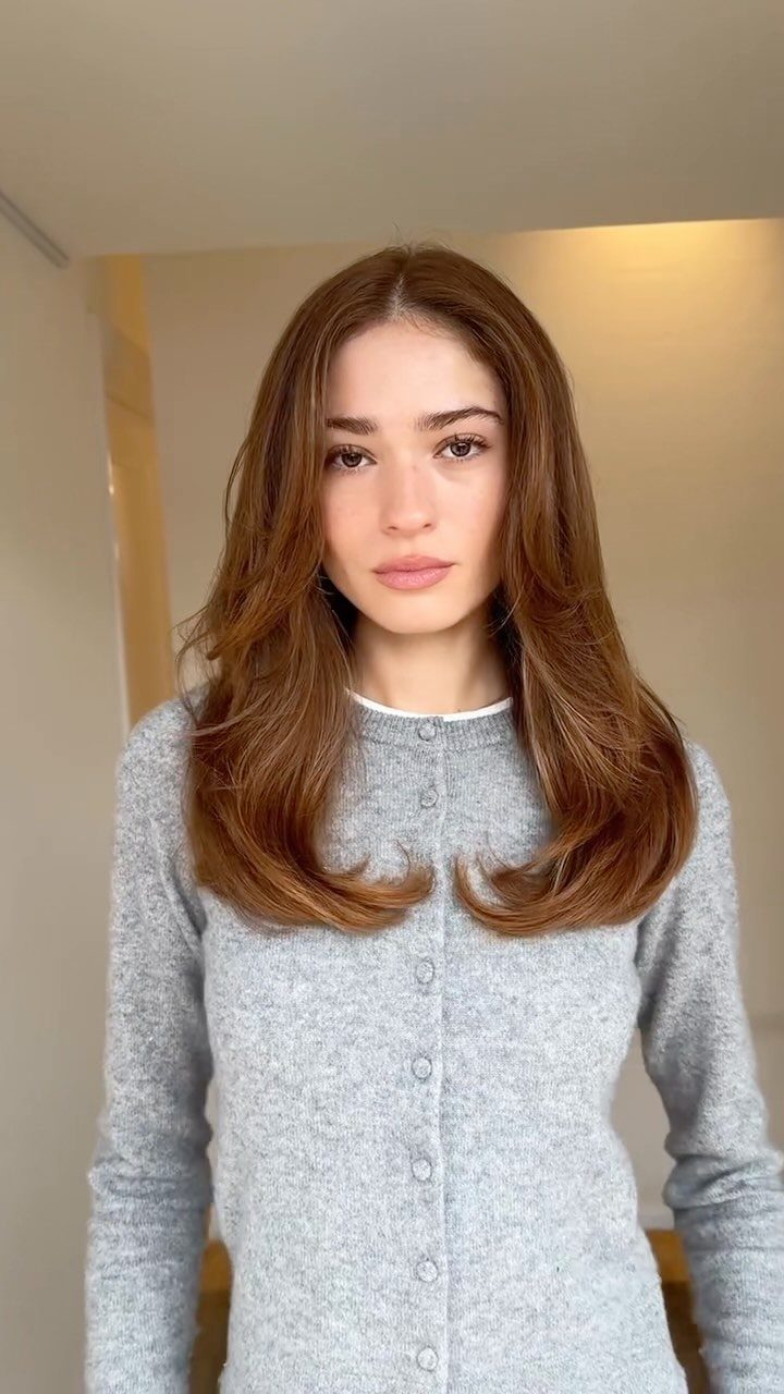 Woman showing long brown U-shaped layers with softly curled ends indoors