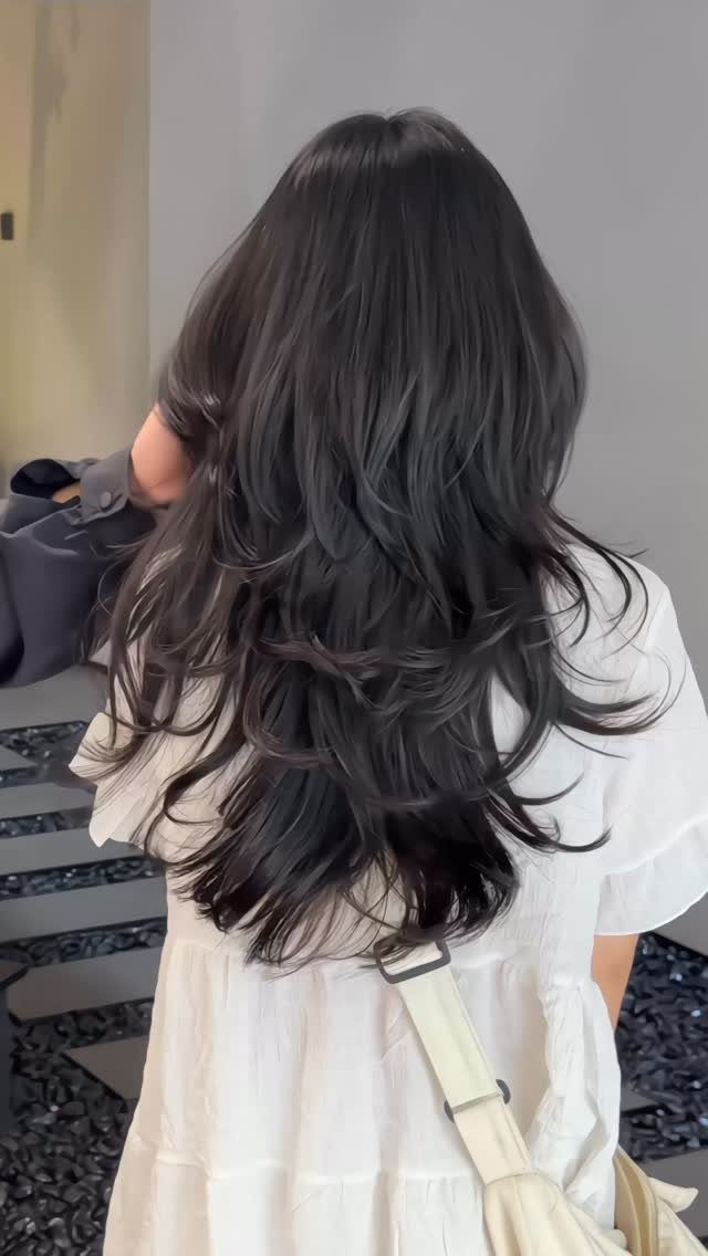 Long dark hair with choppy layers and flipped ends viewed from behind