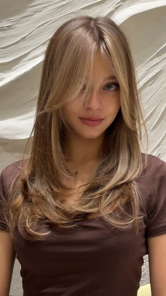 Young woman with long face-framing layers and curled ends