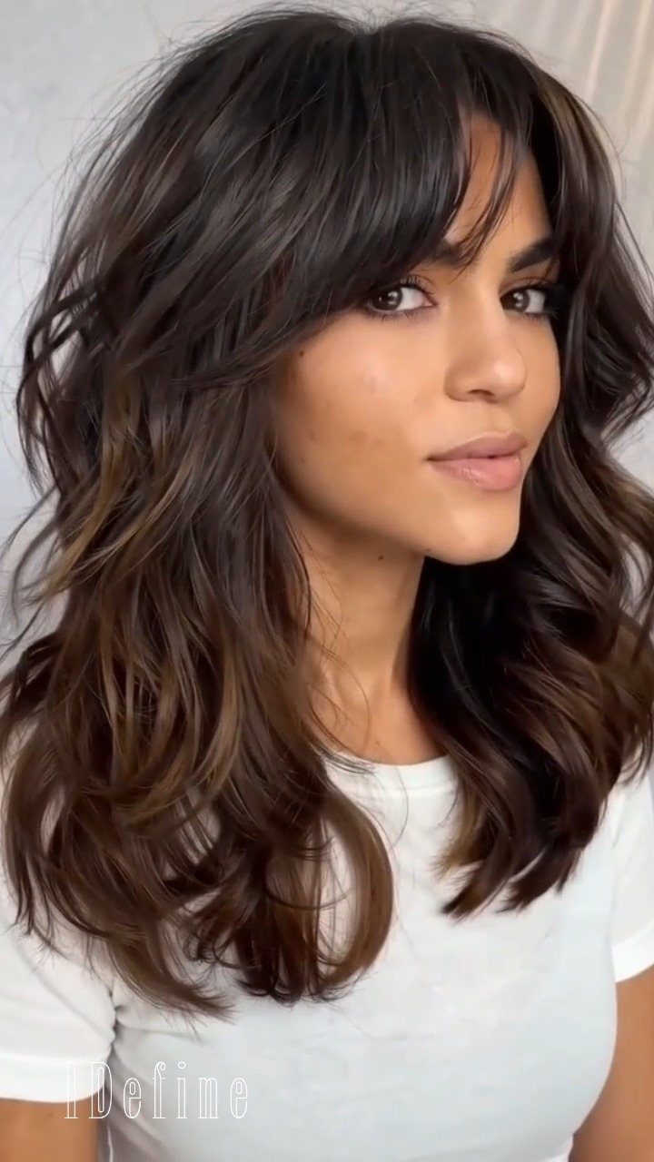 Woman with long dark waves and shorter layers framing her face