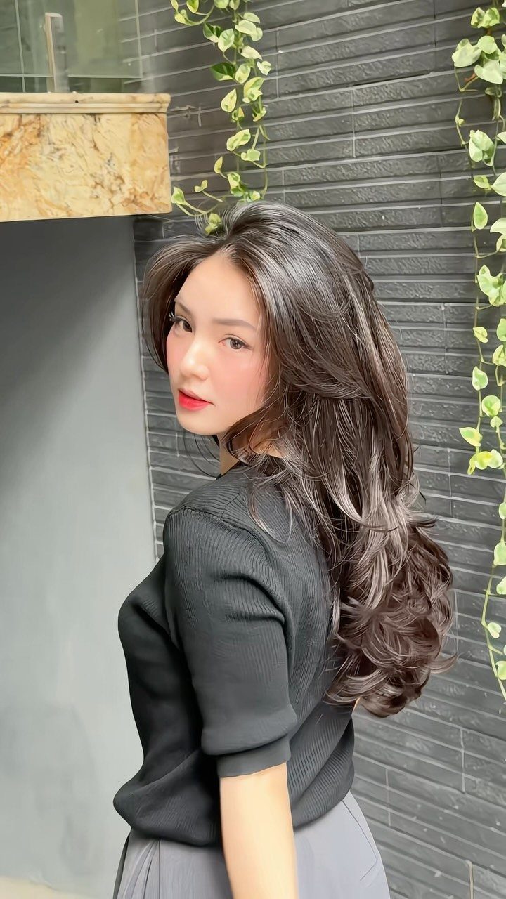 Woman showcasing long dark marquise layers tapering from cheekbones into curled ends