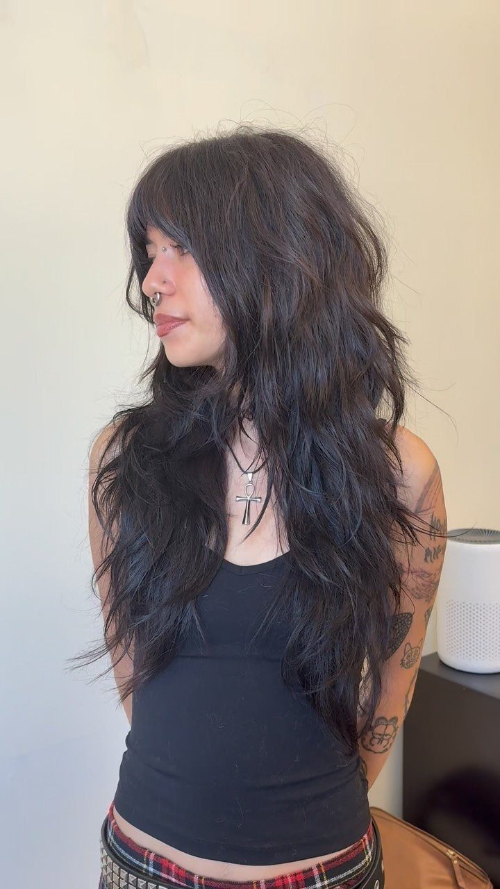 Woman with long dark shaggy layers, tousled waves, and choppy ends