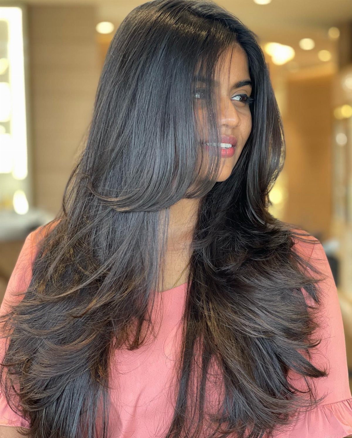 Woman with long, voluminous dark layers swept to one side