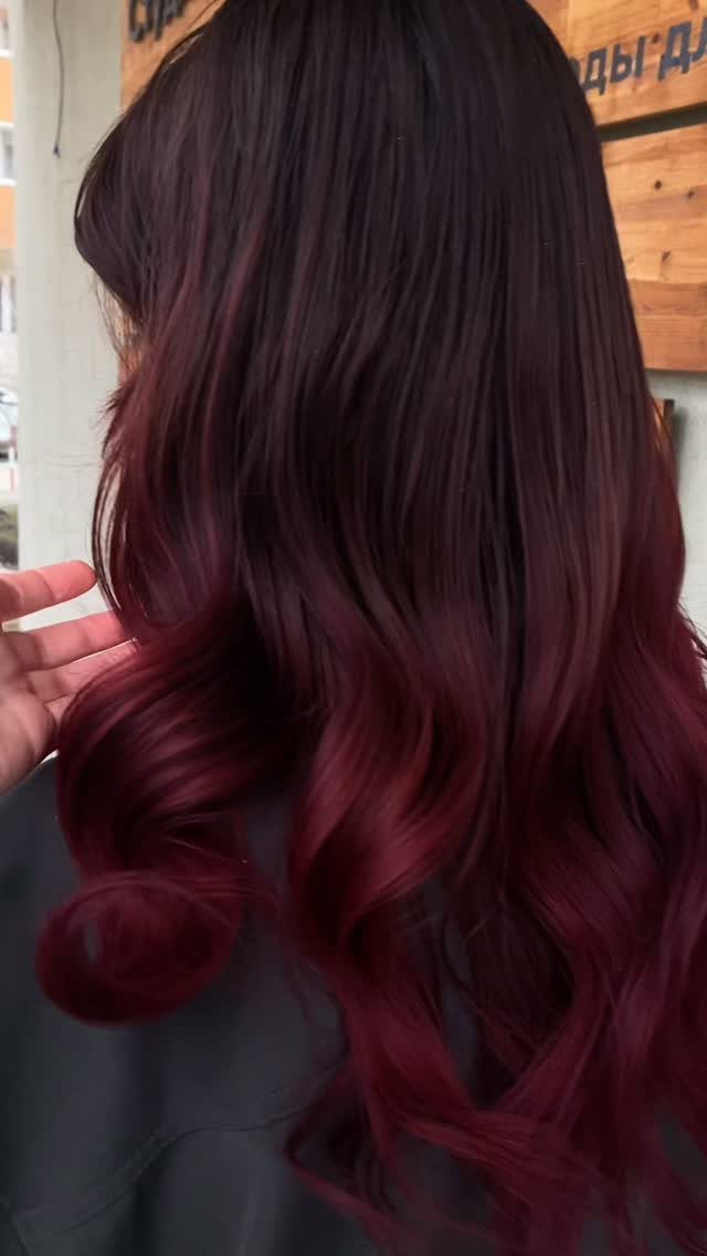 Long dark-brown hair with deep cherry-red highlights in loose curls