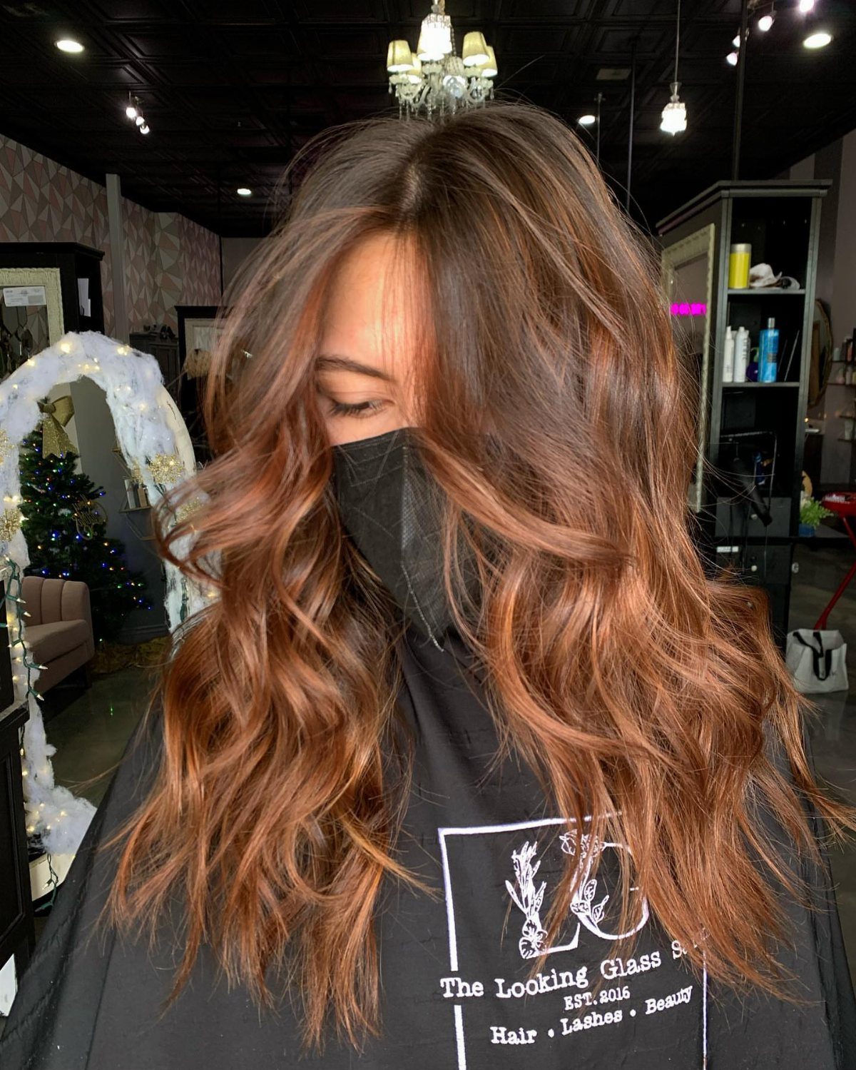 Long wavy brown hair with coppery ribbons displayed in a salon