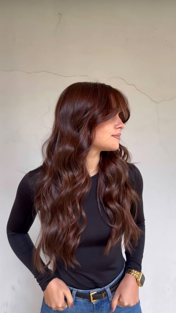 Woman with long dark copper-brown curls wearing a black top