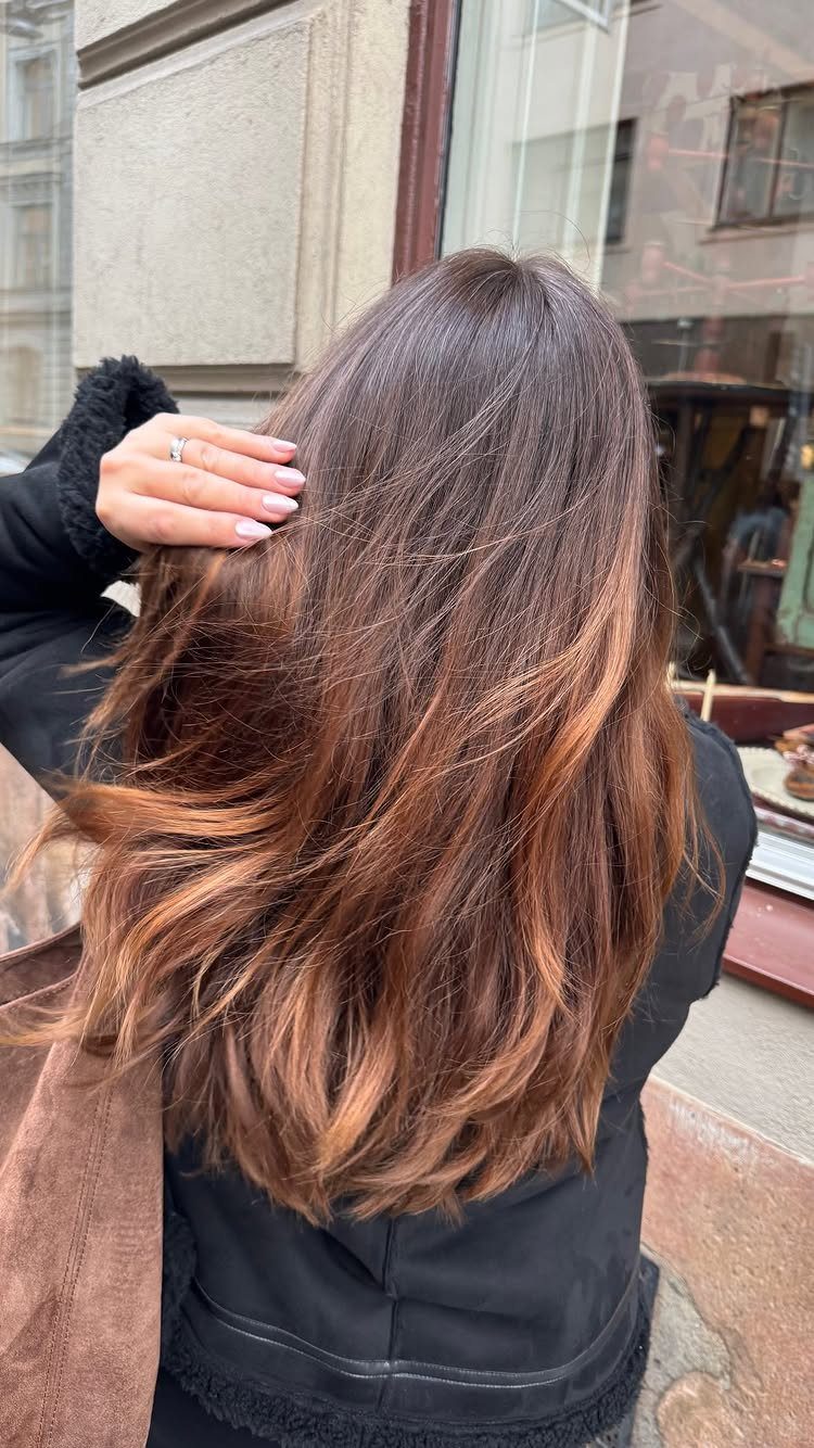 Long layered waves show deep brown hair with warm reddish-brown tones.
