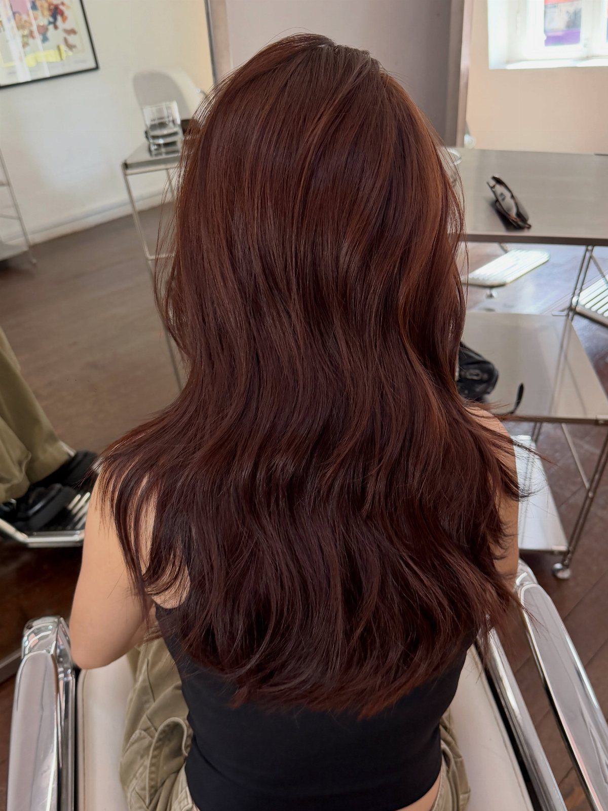 Long layered reddish-brown hair seen from behind in a salon chair