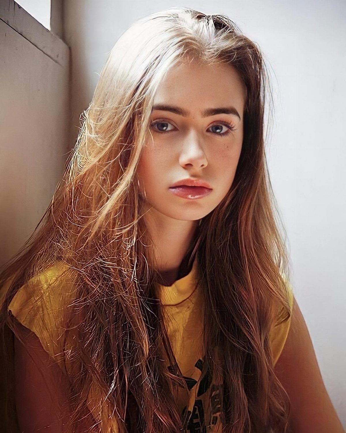 Young woman with long wavy reddish-brown hair and a yellow top