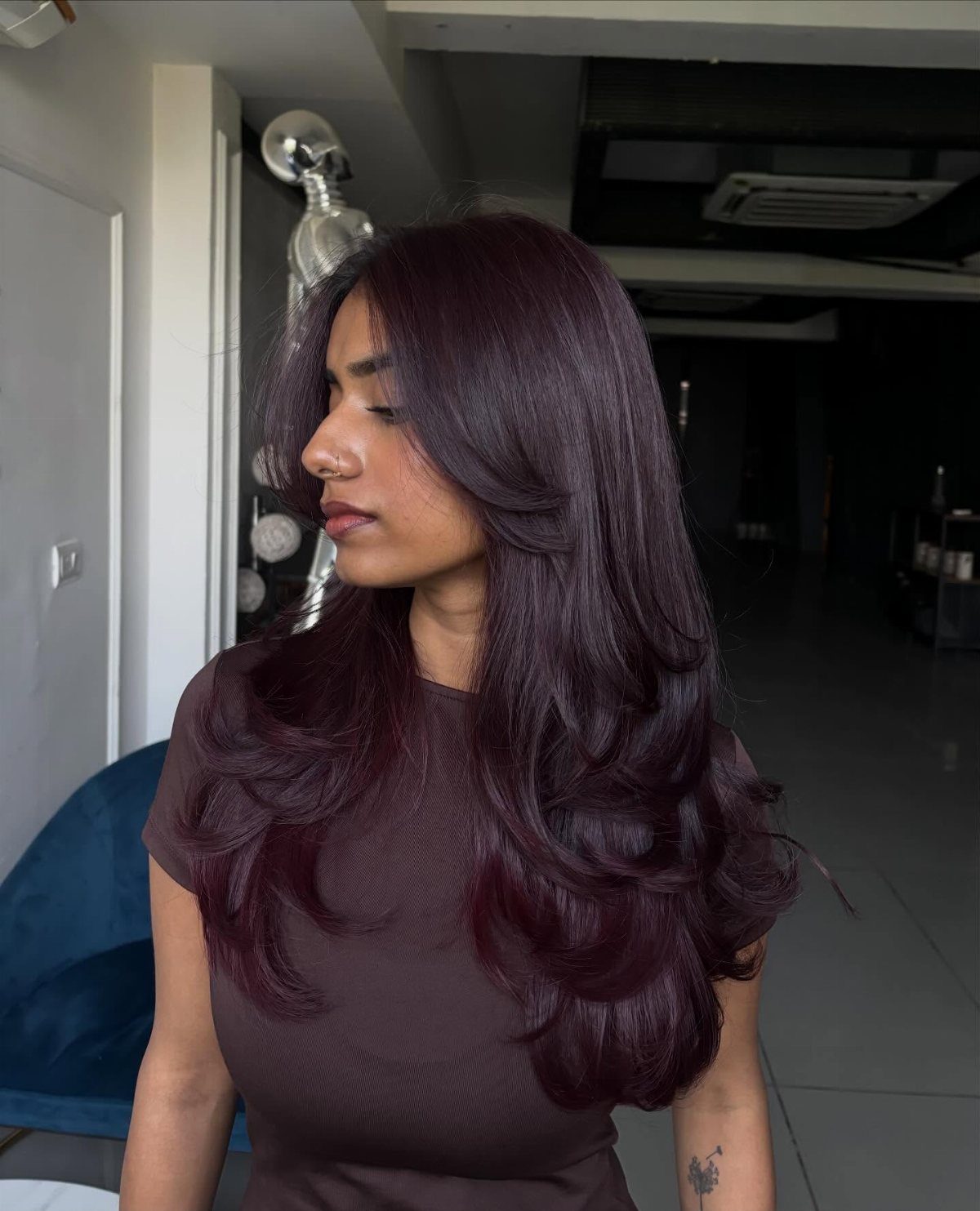 Woman with long, glossy merlot-red brunette hair styled in layered curls