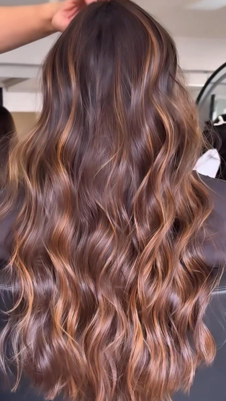 Long wavy red-brown balayage hair with blended coppery highlights