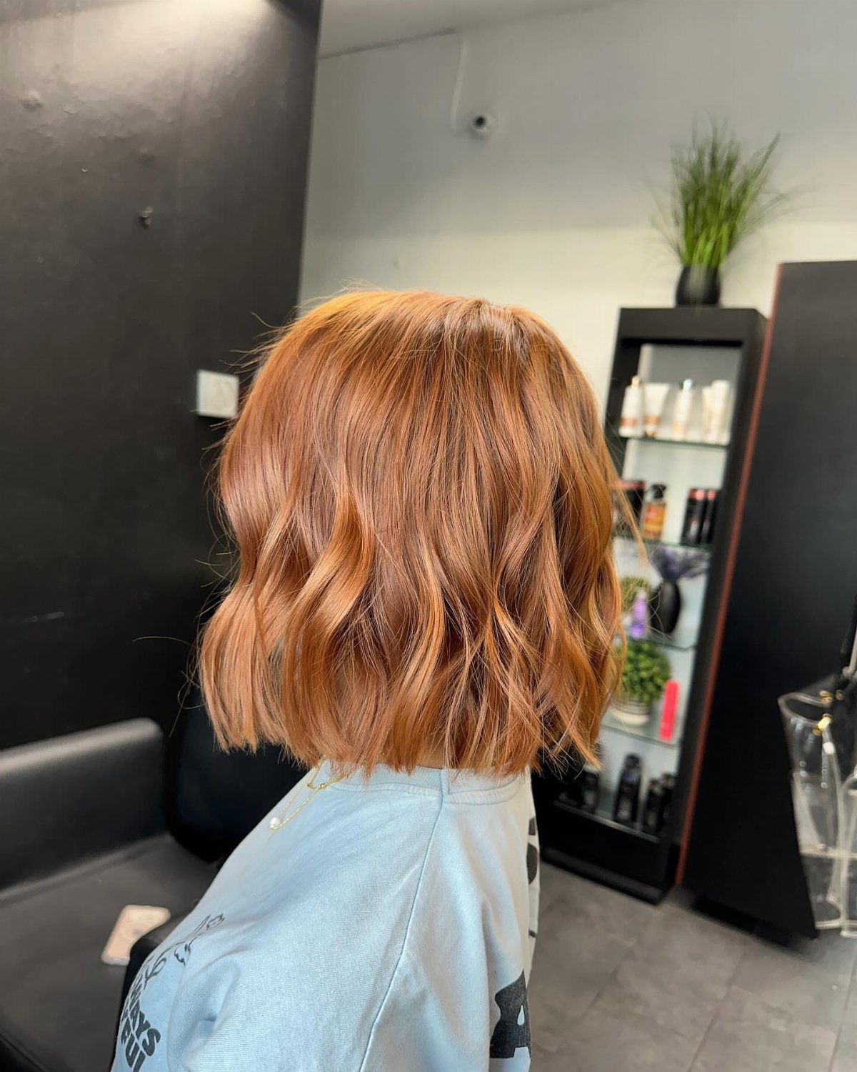 Short wavy ginger bob photographed from behind in a salon chair