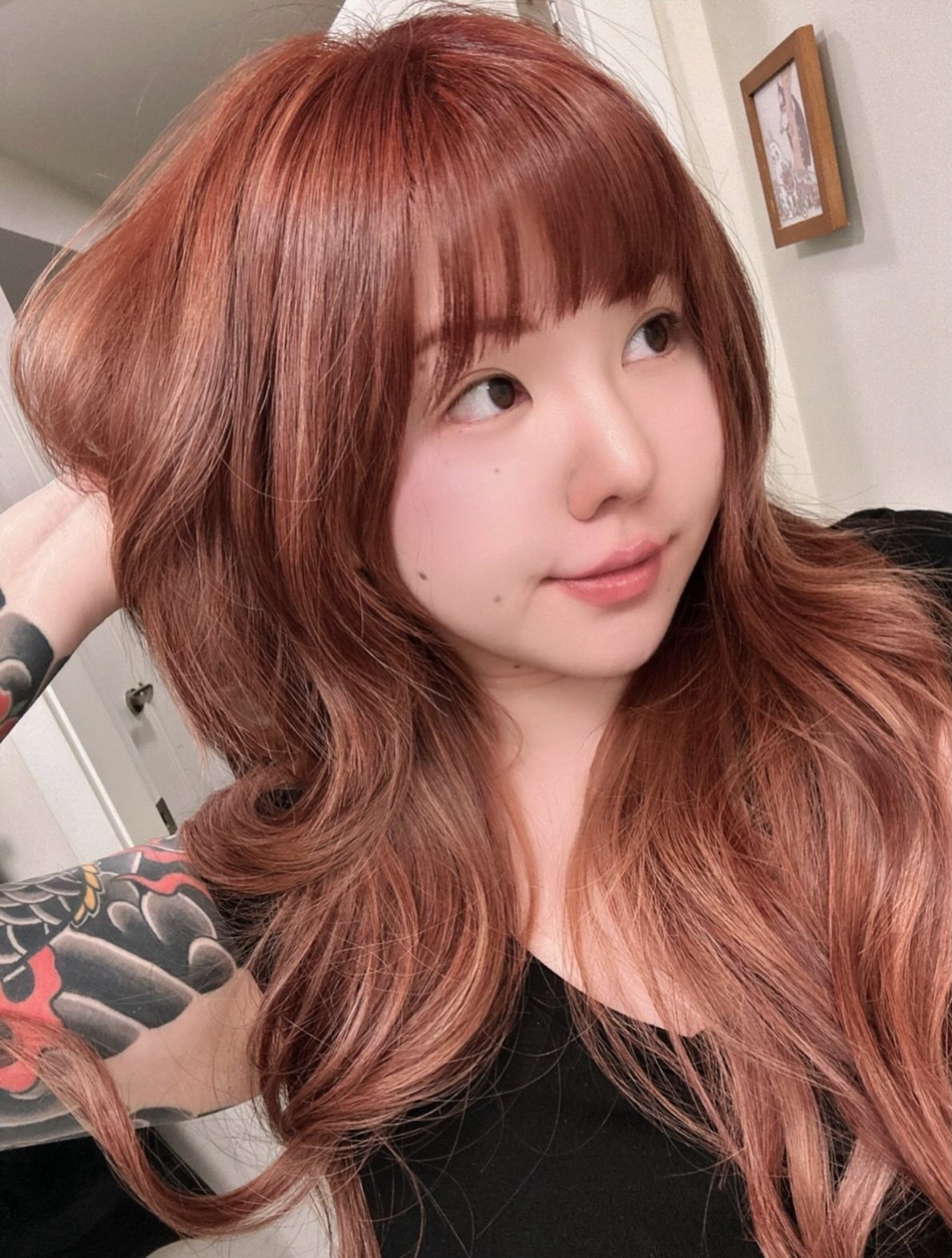 Person with long, wavy auburn hair and straight bangs