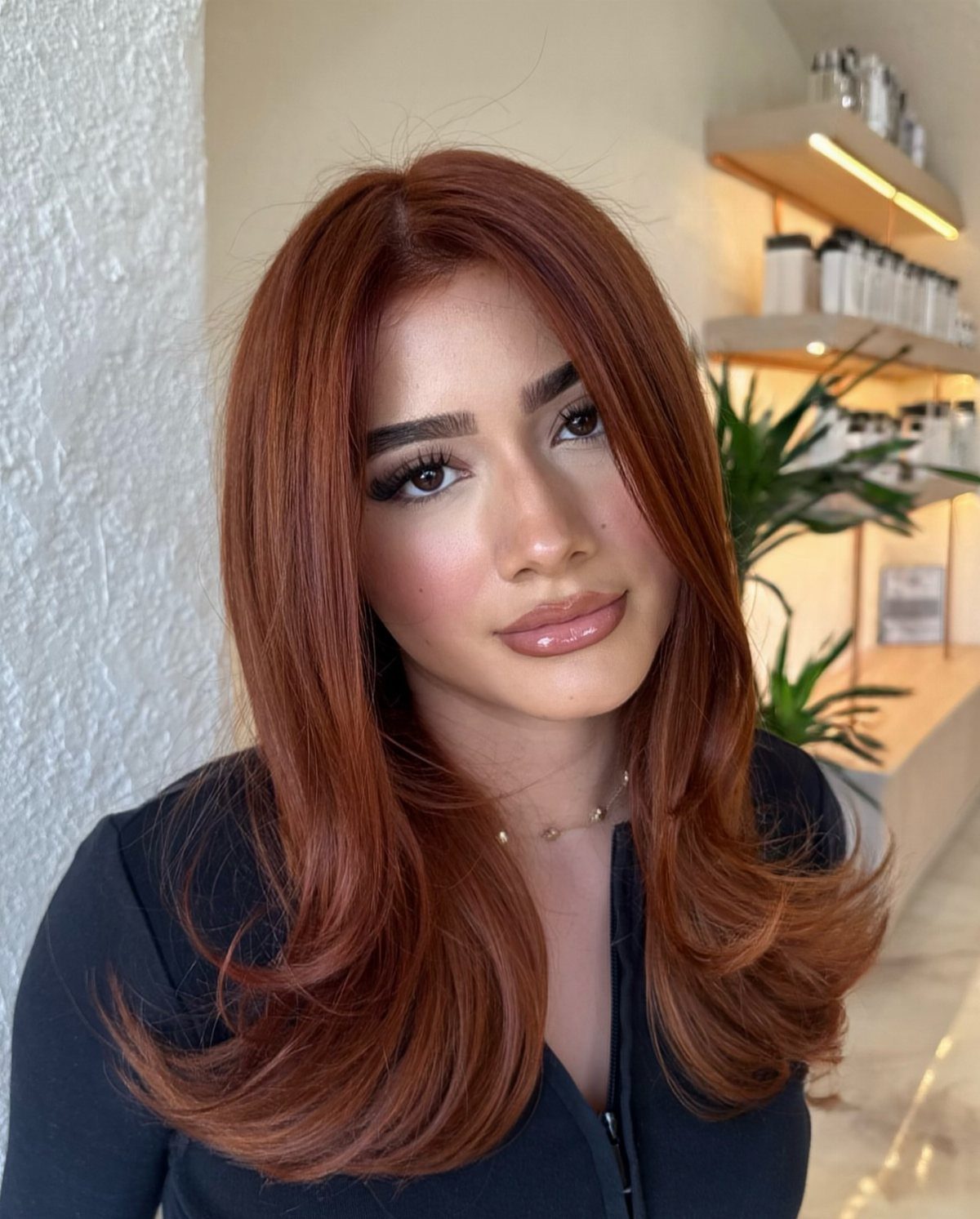 Woman showcasing long, voluminous warm copper-red hair in loose waves