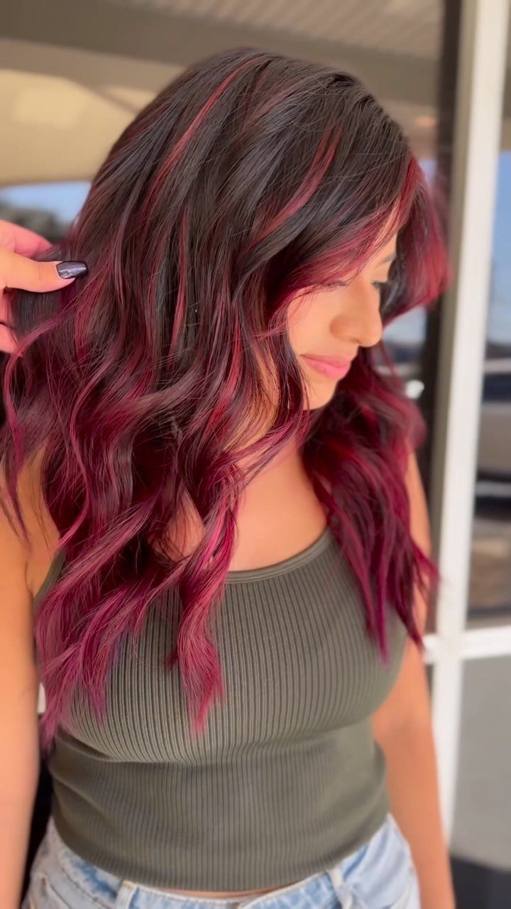 Woman with long dark waves and vivid magenta-red highlights and ends