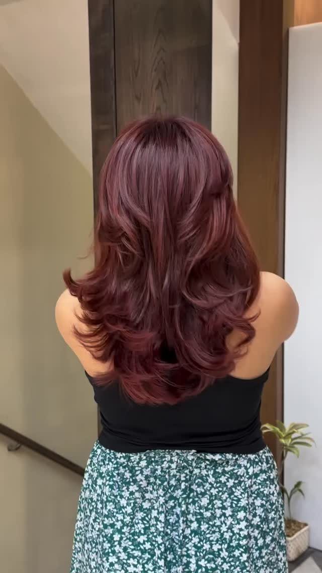 Layered mahogany-red hair with glossy curls viewed from behind