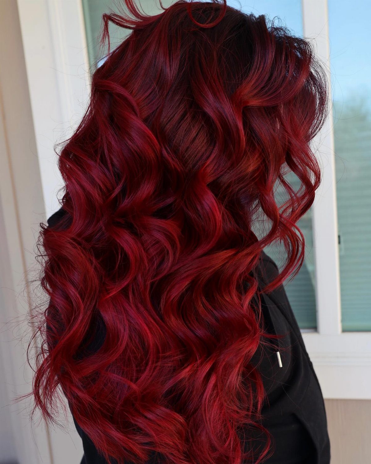 Long curled crimson-red hair with bright scarlet highlights shown from behind