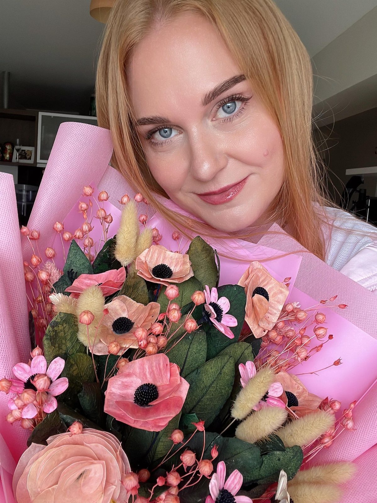 Woman with strawberry-blonde hair holding a large pink flower bouquet