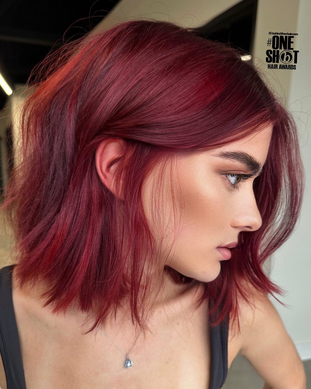 Woman with glossy deep violet-red bob and side-swept bangs