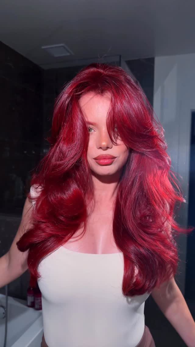 Woman posing with long, voluminous bright poppy red hair