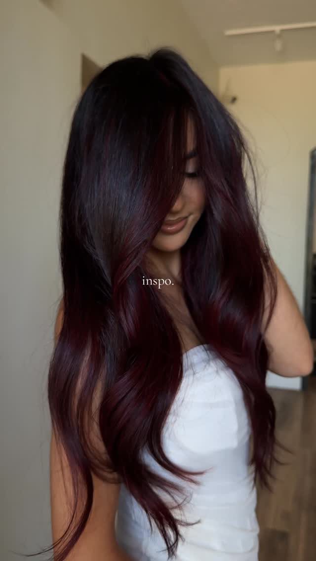 Long wavy burgundy-red hair with deep dark roots on person wearing a white top