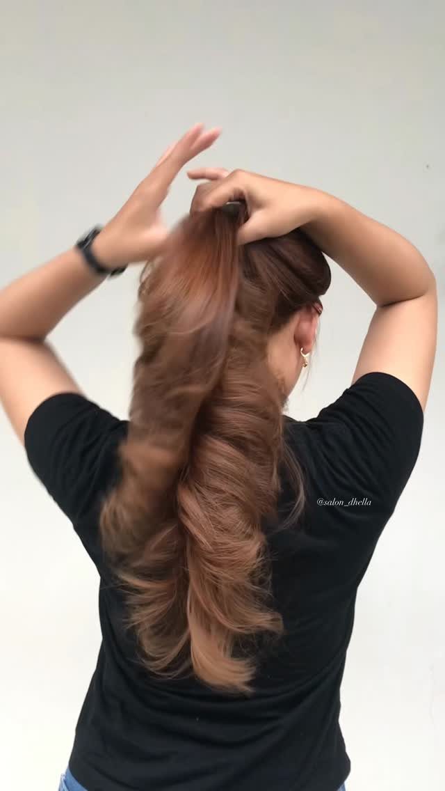 Long wavy medium auburn hair gathered into a ponytail by hand