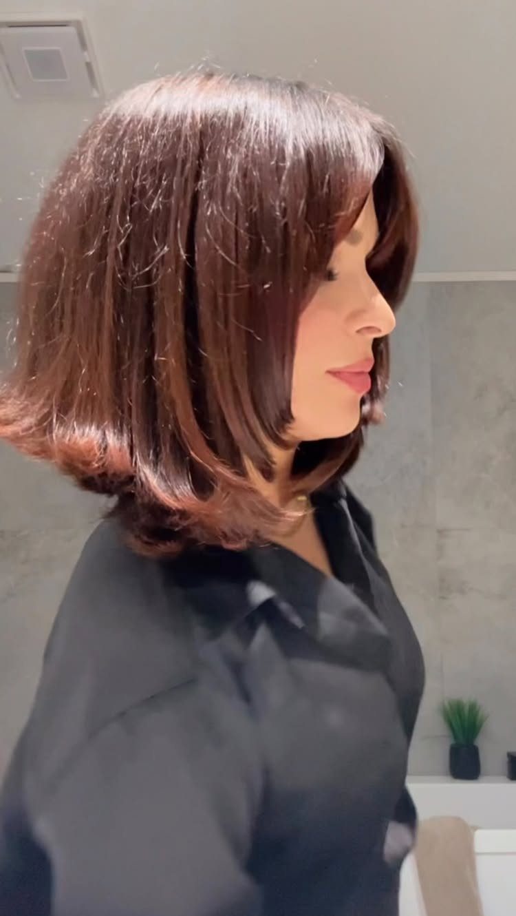 Woman showing a glossy dark auburn bob haircut in a salon