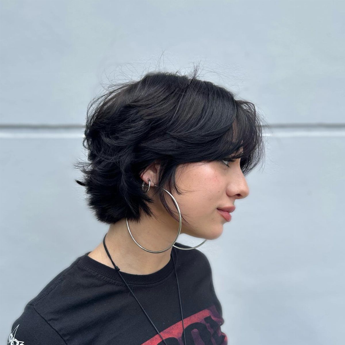 Short dark layered haircut with side-swept bangs and rounded stacked back