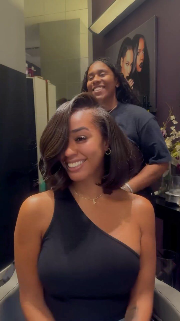 Woman with a smooth, side-parted dark bob seated in a salon