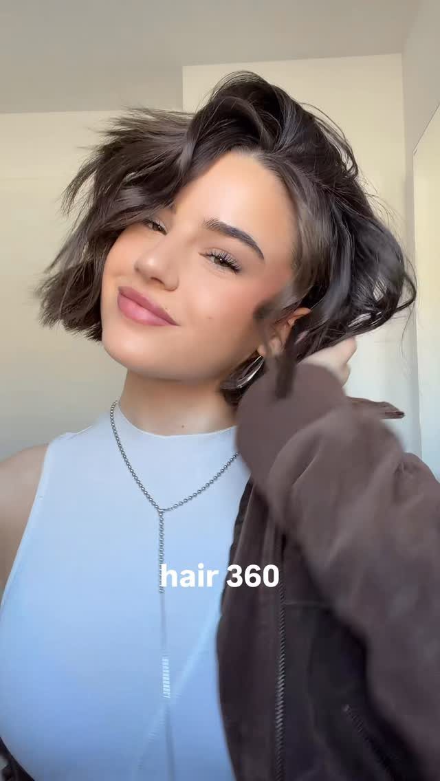 Person showing a short, dark layered bob with side-swept fringe