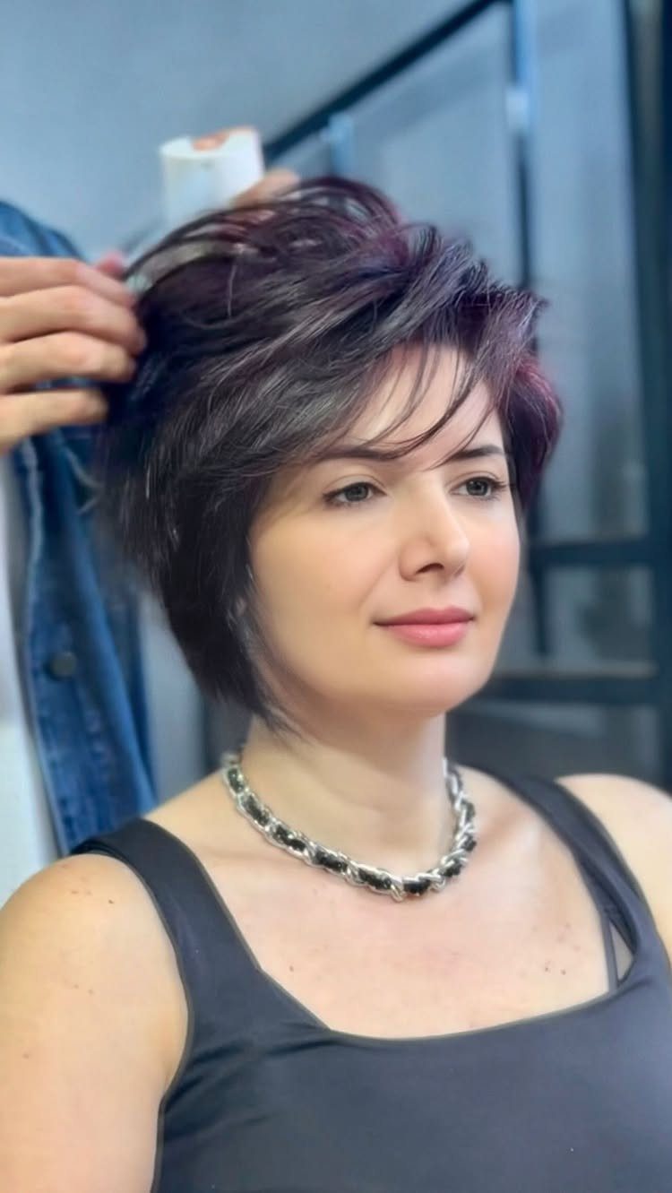 Woman with a short layered pixie-bob and side-swept fringe in a salon