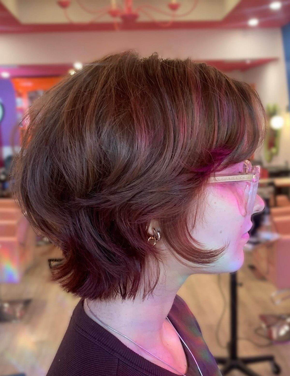 Short softly stacked auburn bixie with curved face-framing layers in a salon