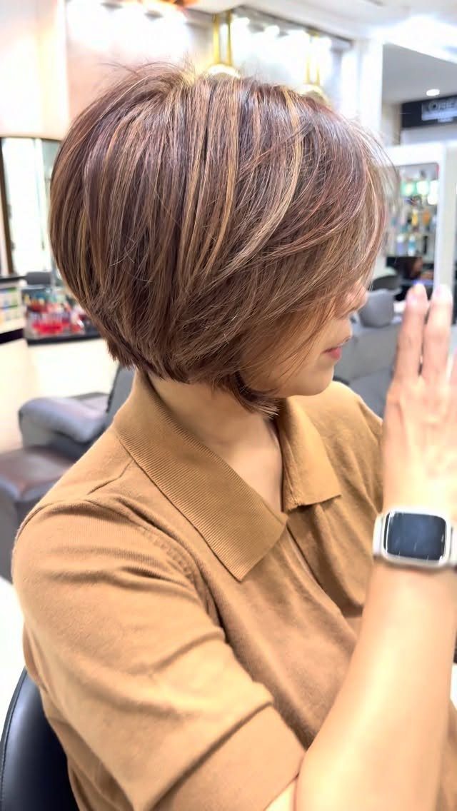 Short layered brown bob with highlighted strands and a rounded salon-finished shape