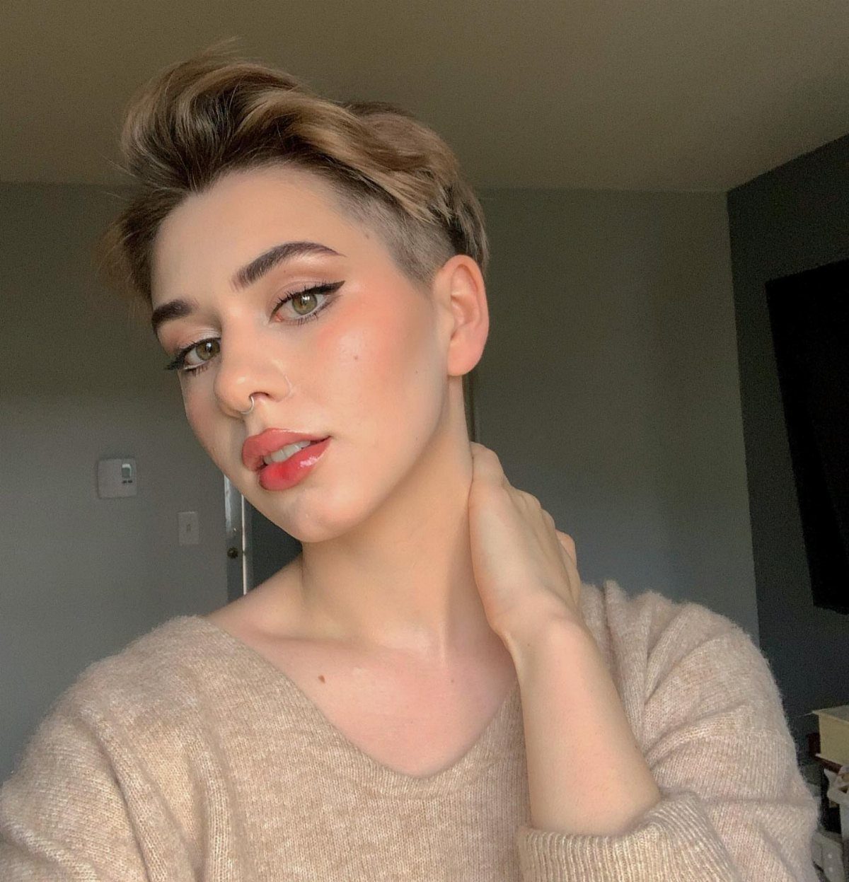 Person showing a short undercut pixie with longer swept-back textured top layers