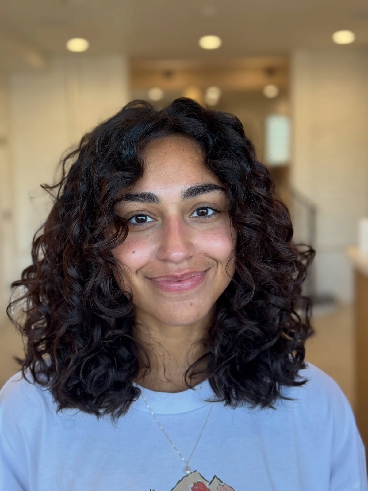 Person with dark, even layered shoulder-length curls facing the camera