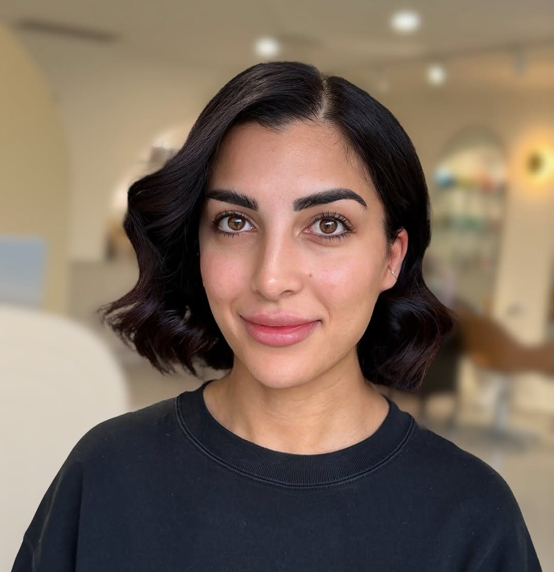 Woman with a dark bob styled in glossy, polished side-parted waves